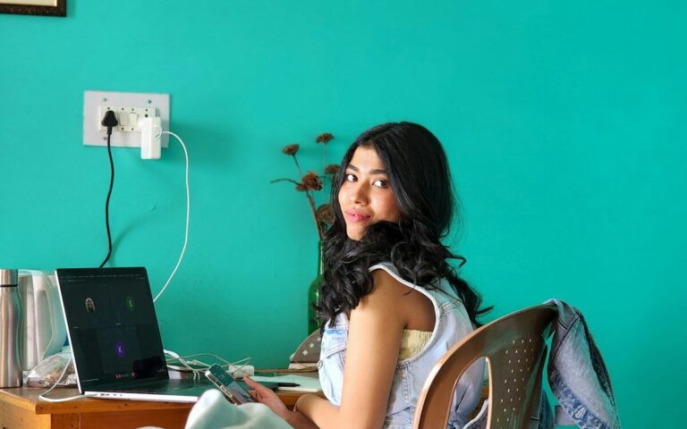 a woman sitting on a bed with a laptop