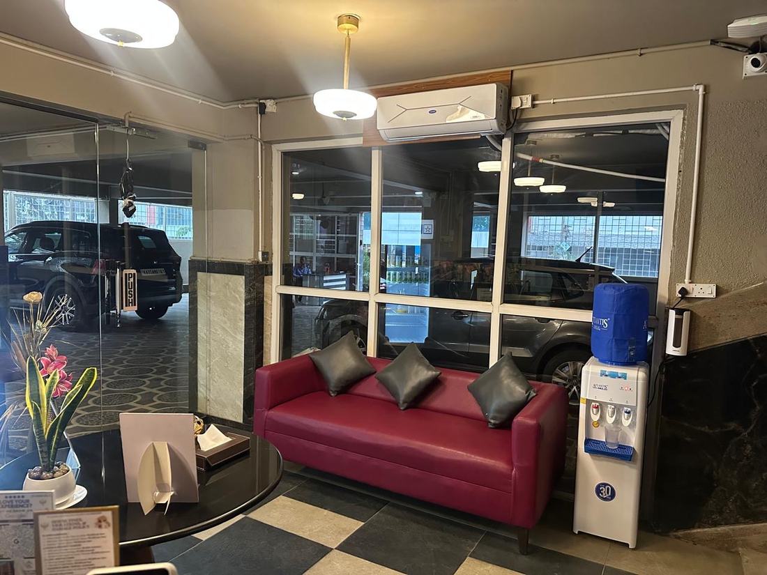 The ground-floor lobby seating with a water dispenser, looking through glass onto the cars parked inside