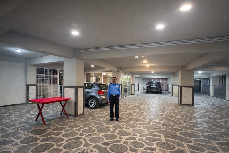 The covered indoor parking, lit, with a uniformed guard on duty and cars in designated bays