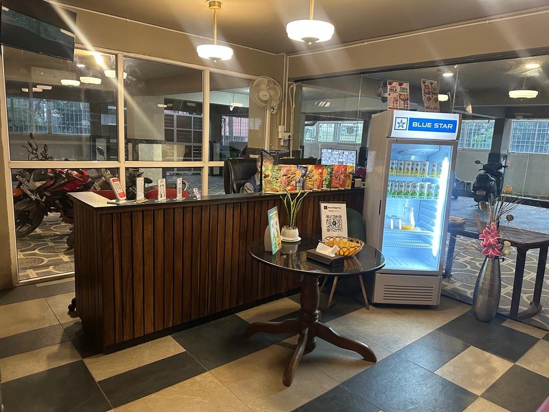 The reception desk in teak panelling, staffed, with a biometric check-in card on the table and a stocked chiller alongside
