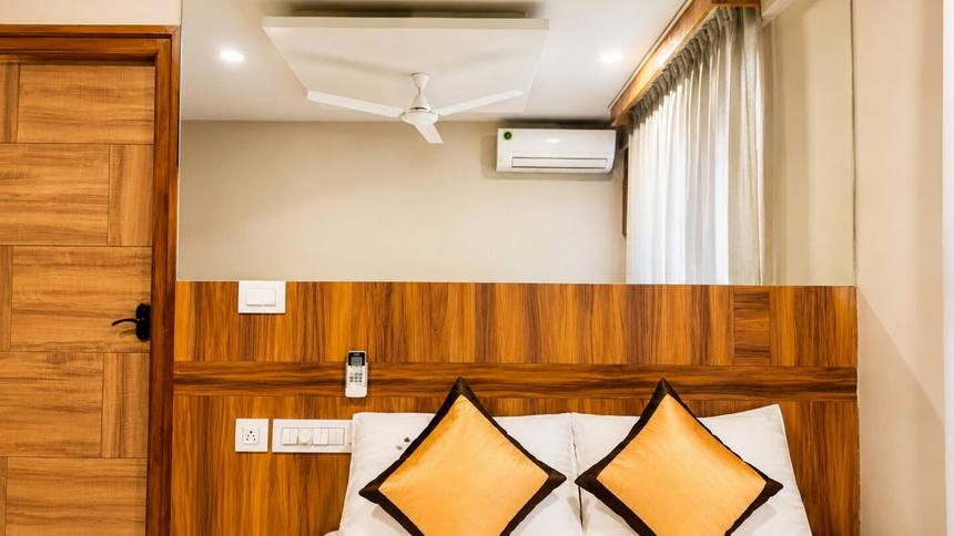 A Standard 1BHK — bed against the panelled headboard wall, air-conditioned, no balcony