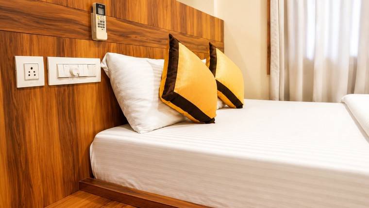 The bedside table and switch panel beside a made bed