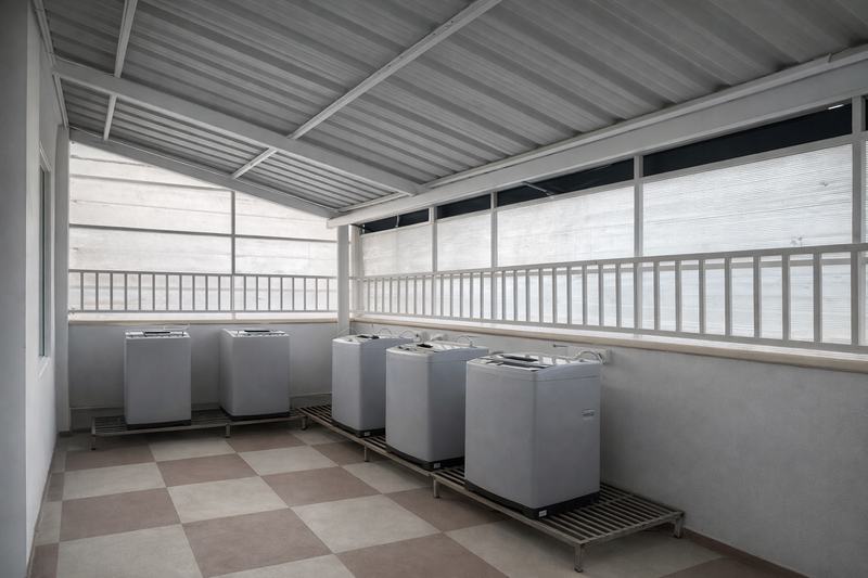 The sixth-floor laundromat with six top-loading washing machines on stands